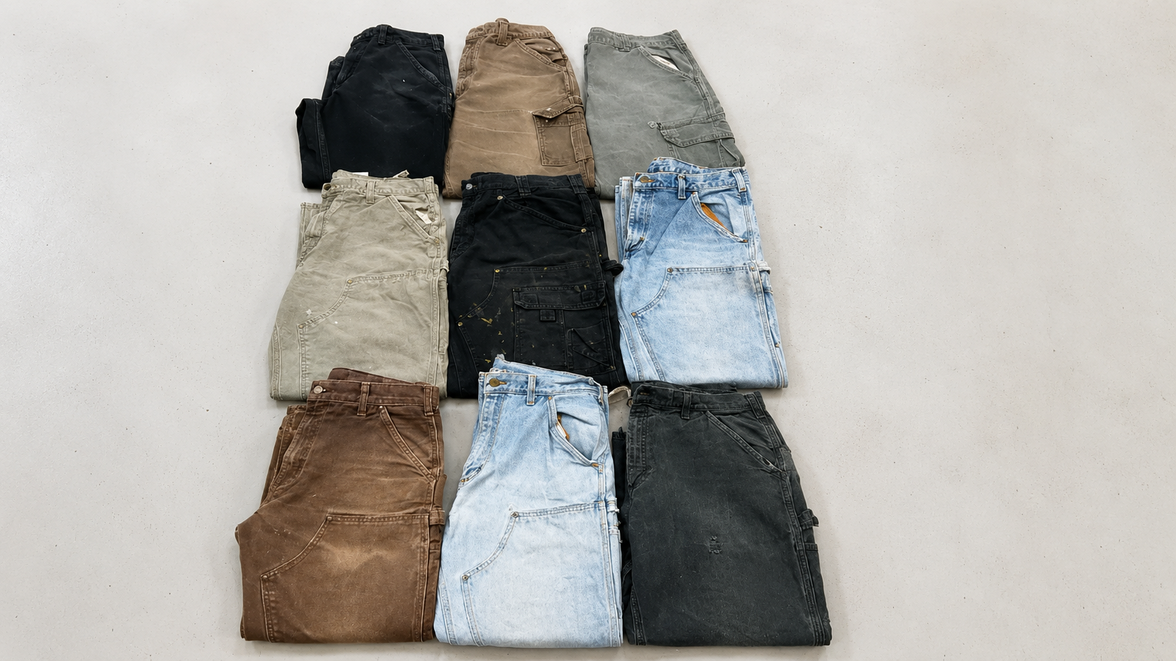 Assorted vintage workwear pants and denim jeans arranged in a flat lay collection